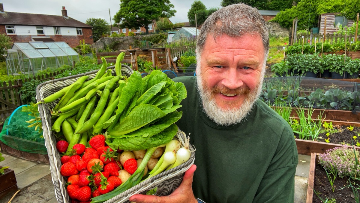 Tony carrying a basket full of freshly picked vegetables